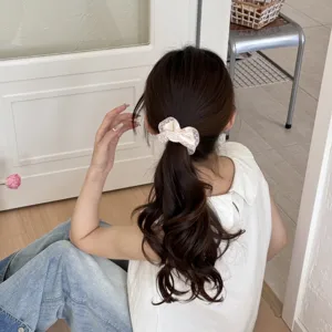 Close-up detail of a sweet cream polka dot hair scrunchie worn on a ponytail in interior scene.