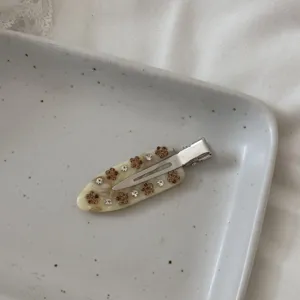 Exquisite acetate hair clip detail, rhinestone floral embellishment, elegant side clip style.