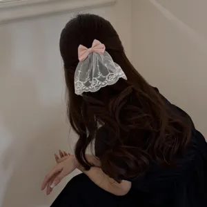 Detailansicht einer süßen rosa Schleifen-Haarspange mit weißem Spitzenschleier im dunklen Haar.