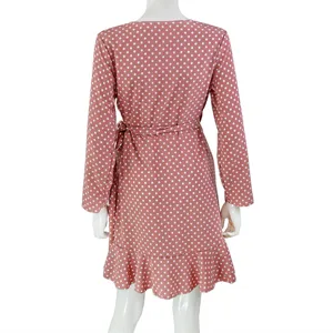 Back view of a trendy pink polka dot long sleeve wrap dress with a chic ruffled hem detail.