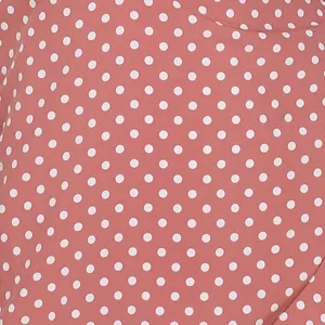 Close-up detail of soft pink fabric featuring classic white polka dots and texture.