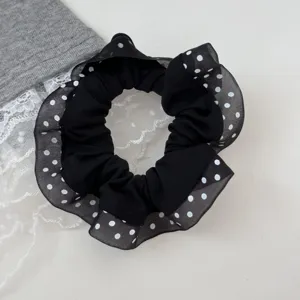Close up of black polka dot hair scrunchie with sheer lace ruffle edge, cute daily accessory.