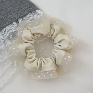 Detail view of a sweet forest-style cream polka dot mesh hair scrunchie with lace trim.