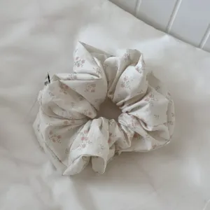 Detailed view of floral hair scrunchie, soft fabric with pink flower pattern texture.