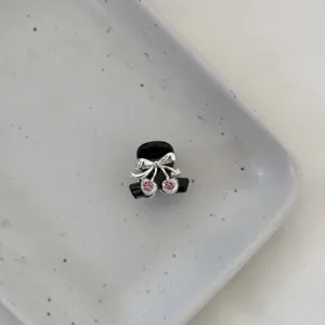 Detailed close-up shot of mini black hair claw clip decorated with sparkling pink rhinestone cherries.