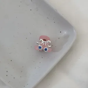 Close-up detail of a cute mini pink hair claw clip featuring a silver bow and blue crystal.