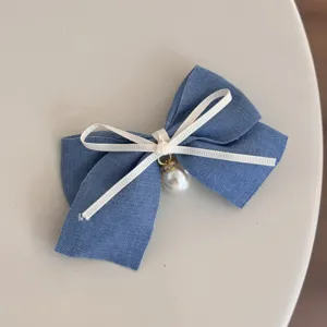 Detailed shot of the blue denim bow hair clip with white ribbon and pearl pendant.