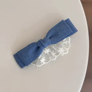 Detailed view of sweet denim bow hair clip with white lace trim, cute girl side clip accessory.