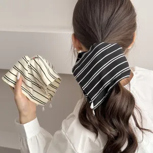 Detailed shot of striped fabric hair scrunchie with pearl pendant for chic low ponytail styling.