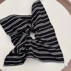 Detailed close-up view of the black and white striped fabric scrunchie with pearl.
