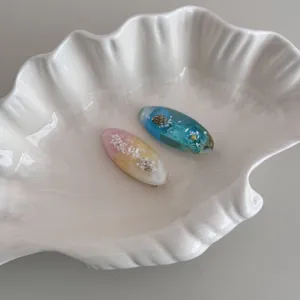 Detailed shot of ocean theme resin hair clip with shell and sand, elegant hair accessory for women.
