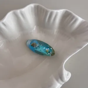 Close-up detail of the ocean style resin hair clip featuring embedded miniature shells.
