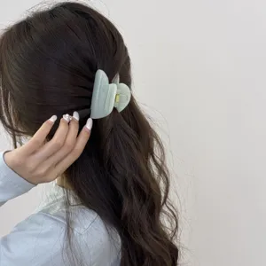 Détail de pince à cheveux cœur vert clair, accessoire de coiffure esthétique doux.