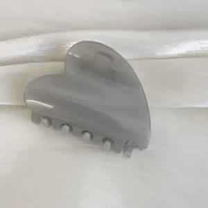 Détail de pince à cheveux cœur grise brillante, finition scintillante, accessoire doux.