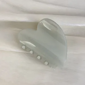 Détail de pince à cheveux cœur nacré, finition brillante élégante, maintien sûr pour coiffure.