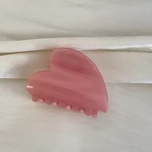 Détail de pince à cheveux cœur rose, accessoire en résine au style doux pour coiffure quotidienne.