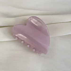 Gros plan détaillé d'une jolie pince à cheveux en forme de cœur violet clair pailleté.