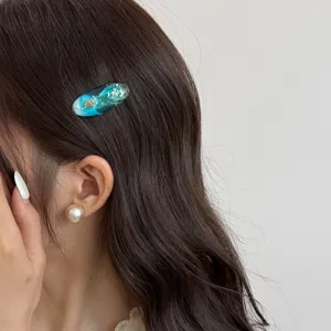 Ocean style resin oval hair clip with shell and glitter, side wearing main product view.