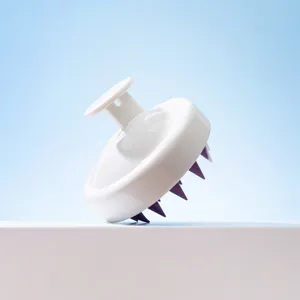 Detail de brosse de massage du cuir chevelu en silicone avec manche blanc et poils lila.
