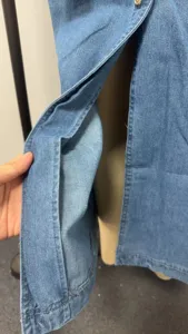 Detailed view of the sleeveless long denim dress side slit and fabric texture features.