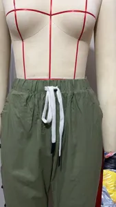 Green casual pants detail, elastic waistband, white drawstring with black tips, soft fabric.