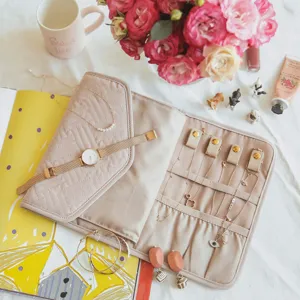 Beige quilted jewelry roll detail, portable travel organizer for earrings and necklaces.