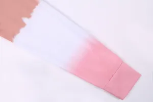Close-up detail of a soft gradient tie-dye long sleeve sweatshirt cuff in pink and white.