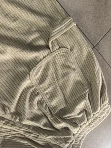 Close-up view of men's corduroy casual pants detail, showing pocket and textured fabric.