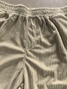 Corduroy casual pants detail showing elastic waistband and fine ribbed texture fabric.