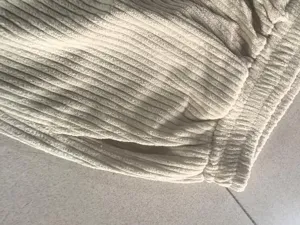 Close-up of mens corduroy casual pants, showing soft ribbed fabric texture and elastic waist.