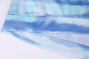 Blue tie-dye gradient fabric detail view, showing fine stitching and soft texture for apparel.