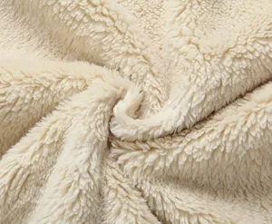 Primo piano di morbido tessuto in pile sherpa beige, che mostra una spessa consistenza calda.