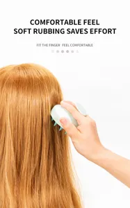 Detail view of mint green silicone scalp massage brush showing finger grip during use on hair.