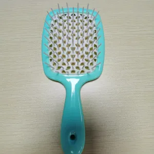 Brosse à cheveux creuse bleue avec maille en nid d'abeille et poils blancs pour coiffage.