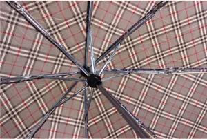 Vue détaillée de l'intérieur d'un parapluie pliant à 3 volets avec motif à carreaux et baleines.
