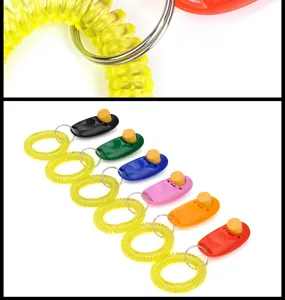 Dettaglio in primo piano del cinturino a molla giallo e del clicker per animali colorato.