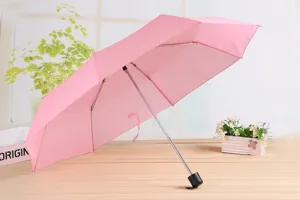 Vista dettagliata dell'ombrello pieghevole rosa che mostra la tela e il telaio robusto.