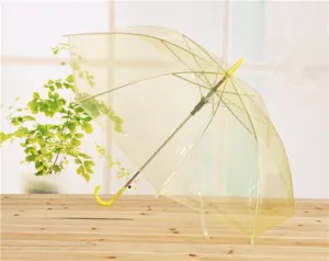 Paraguas largo transparente con mango amarillo, vista de detalle estilo fresco para días lluviosos.