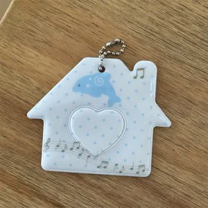 Close-up detail of cute house-shaped photocard holder with blue dolphin design and heart window.