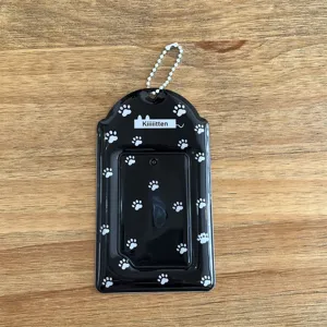 Vue détaillée du porte-carte noir avec empreintes de pattes et chaîne de perles blanche.