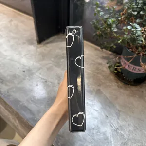 Detail shot of black photocard binder spine featuring white heart patterns and metal ring hole.