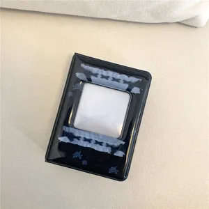 Detailed close-up of a black mini photocard binder with cute rose and lace pattern.