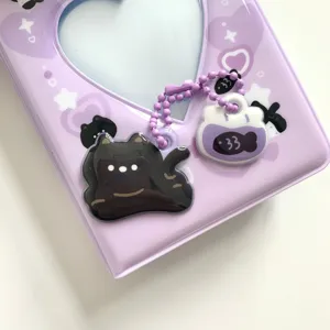 Close up of cute purple photocard binder with acrylic cat and fish charms on beaded chain.