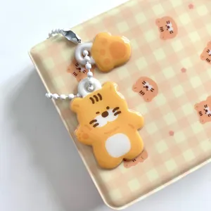 Close up view of cute acrylic tiger and paw charm keychain with bead chain on cute box.