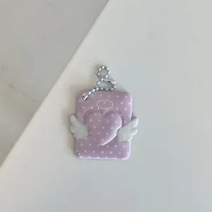 Close-up detail of cute pink polka dot angel wings heart card holder pendant with pearl chain