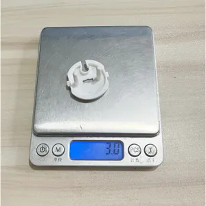 Detailed shot of white French socket safety cover showing product weight on scale clearly.