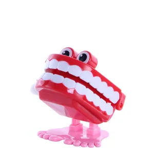 Rotes Aufzieh-Zähne-Spielzeug mit großen Augen und rosa Füßen, lustiges Neuheits-Geschenk.
