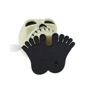 Gros plan sur le jouet à remonter en plastique blanc tête de mort avec pieds noirs pour Halloween.