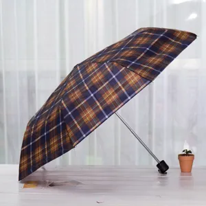 Détail de parapluie pliable compact, design portable à trois plis avec motif à carreaux.