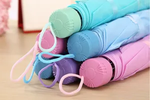 Vue détaillée de parapluies capsules pliables mini portables colorés, design avec cordon.